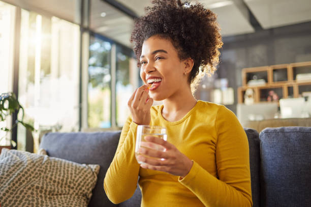Smiling woman taking a daily supplement at home